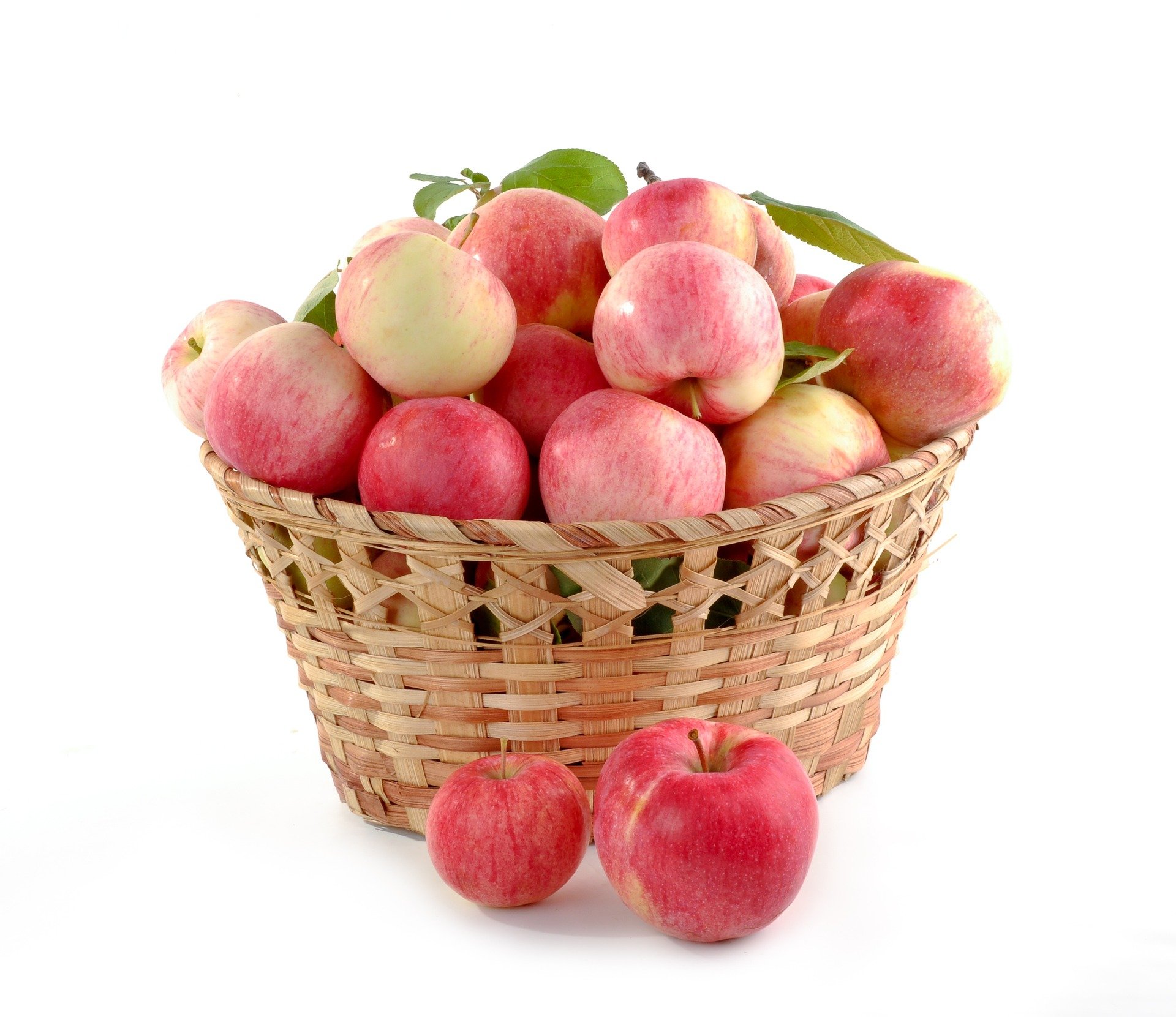 Picture of several red apples in a brown wicker basket. Two of the apples are in front of the basket.